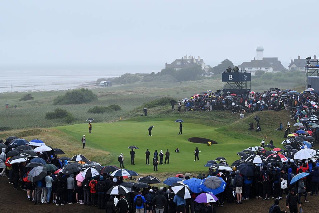 Umbrellas surround the 13th green on a day of persistent rain